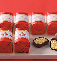 Marzipan Klassiker der Firma Niederegger in zwei Reihen aufgereiht, eingepackt in rote Wickler mit einer weißen Banderole. Auf der rechten Seite ist ein Klassiker angeschnitten worden.